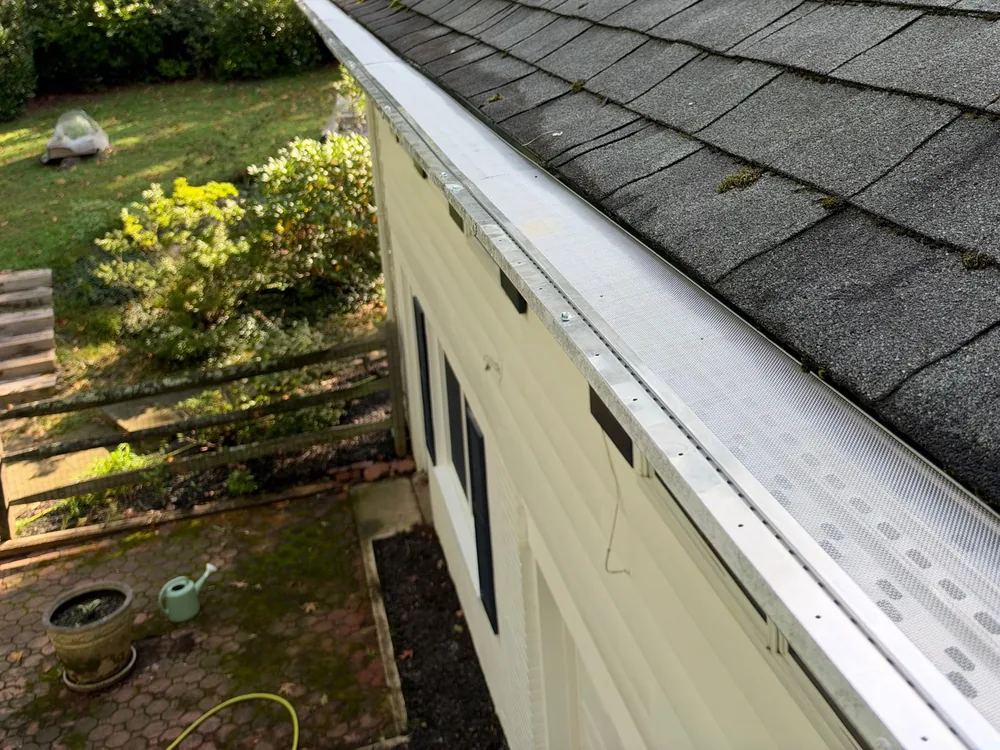 Same gutter with a micro mesh gutter guard installed along the roof edge