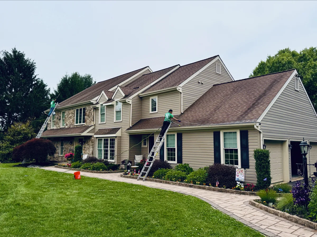 ClearFlow crew hand cleaning gutters on ladders at a two-story home in West Chester PA