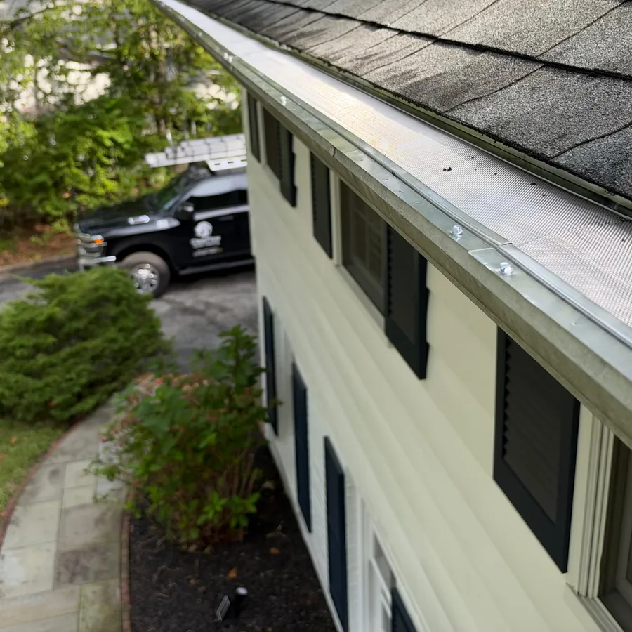 Close-up of micro mesh gutter guard on a two-story home with a ClearFlow truck in the driveway