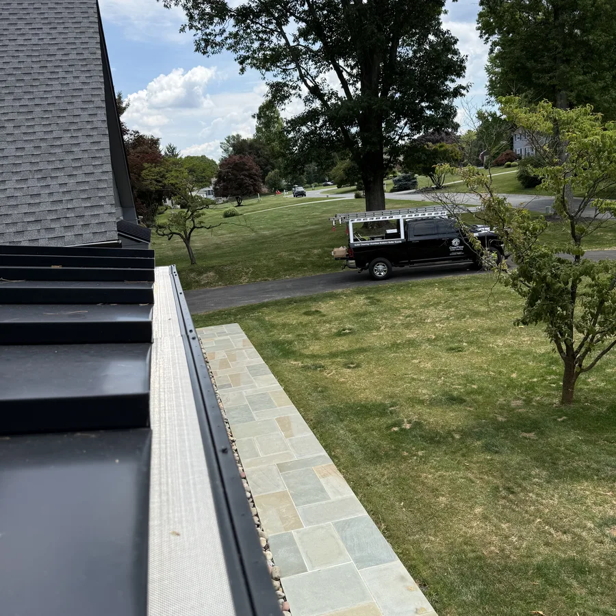 Gutter guard on a metal roof edge with ClearFlow truck parked in the driveway